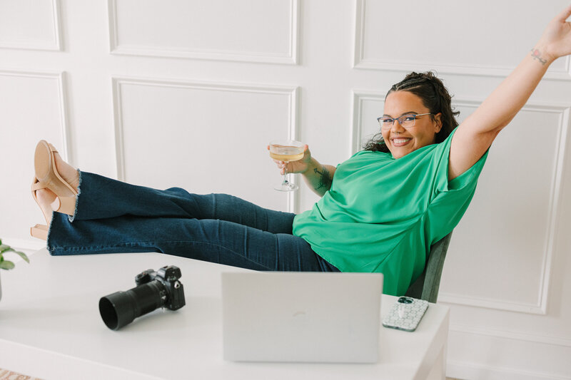 A person sitting in a chair with their feet up holding a cocktail glass in one hand