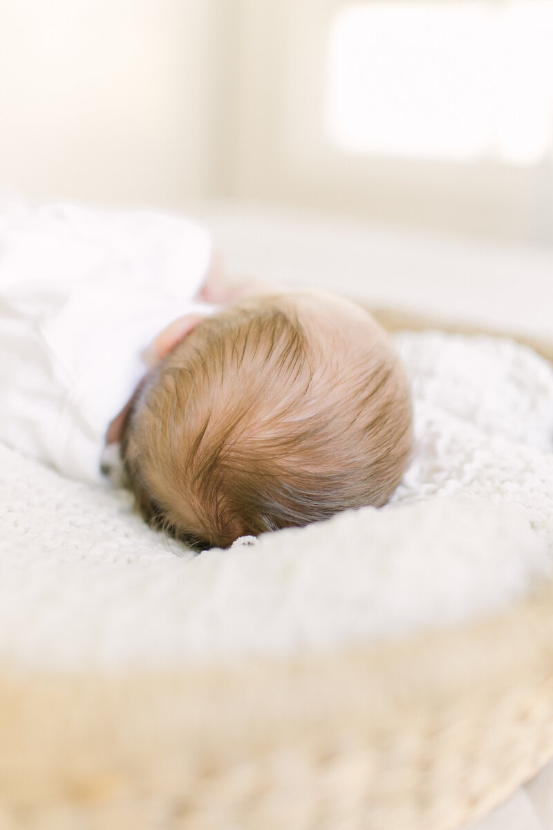 Newborn baby sleeping in moses basket during lifestyle newborn session with Boston Area Newborn Photographer