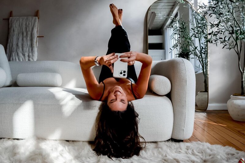 Lifestyle photo of Emily Michele relaxing on a sofa, symbolizing balance, self-trust, and feminine flow within her Unveiled embodiment coaching brand.