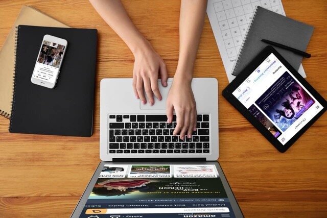 Author using laptop for book marketing and promotion, with smartphone and tablet showing social media and book cover
