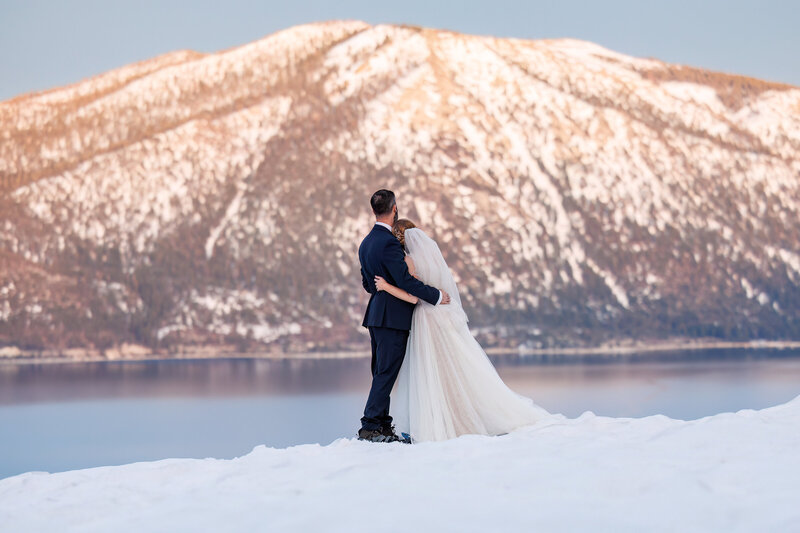 A couple looks out at Lake Tahoe during their snowy mountain elopement in California.