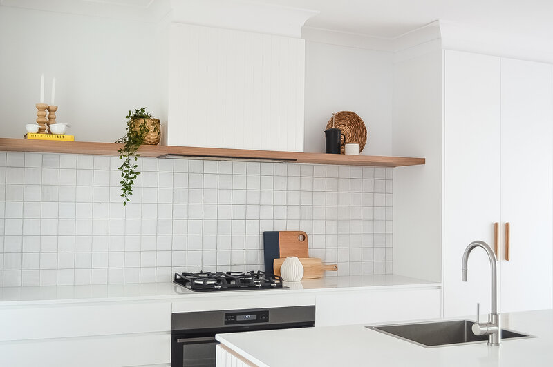 Modern kitchen with white cabinets, a gas stove, a tile backsplash, and a stainless steel sink, expertly crafted by Newcastle Kitchen and Bathroom Designer for a seamless blend of functionality and style.