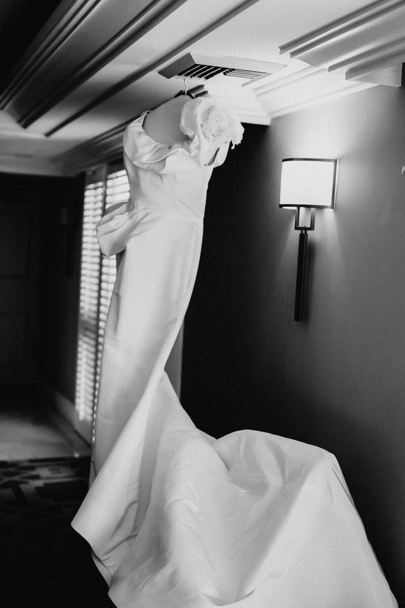 Bridal dress hanging in the hotel room for bride  before she gets dressed for her wedding.