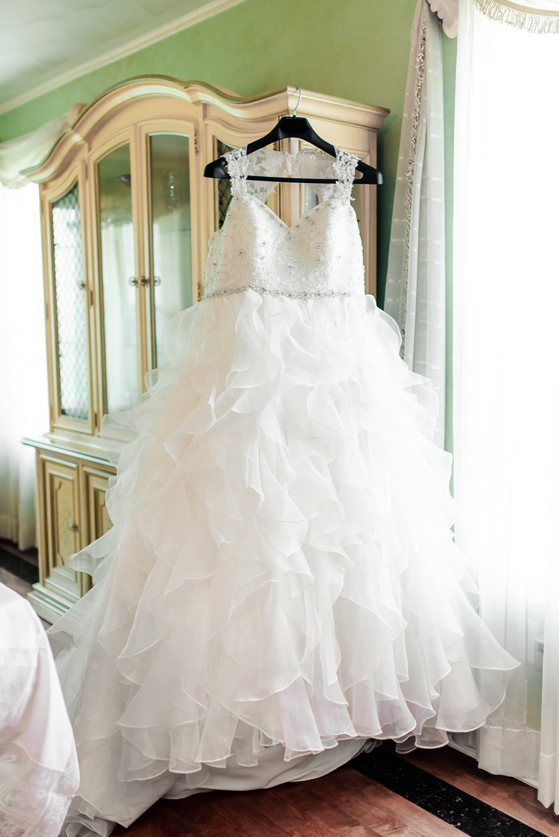 Wedding gown hangs from the corner of a china cabinet