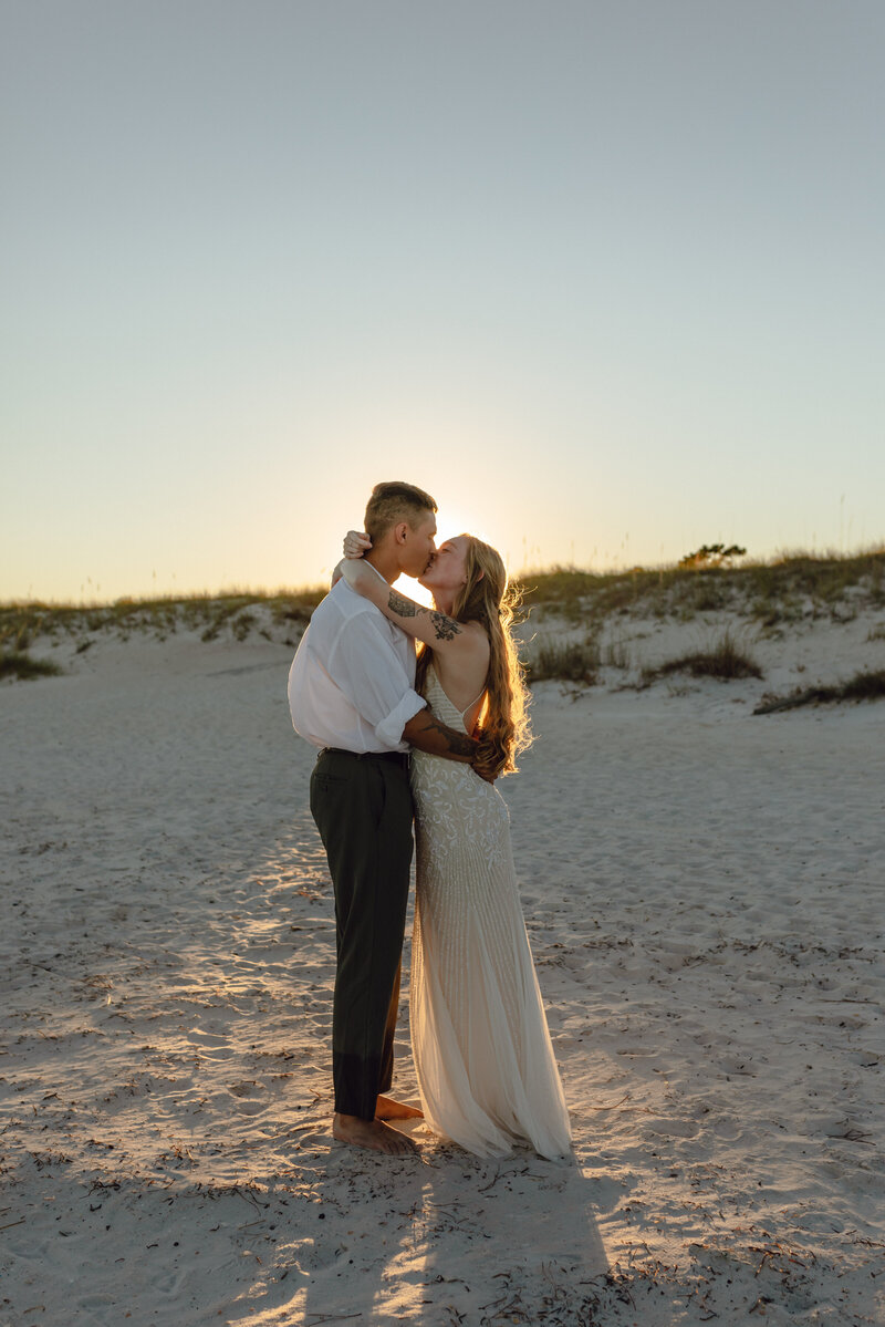 newlyweds embrace backlit by sun directly after their ceremony in Panama City Beach Florida
