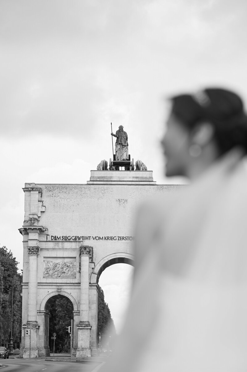 Braut steht vor dem Siegestor in München und lächelt ihren Mann an