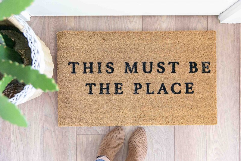 Brown outdoor mat "This Must Be The Place" mat rug with brown boots on the side