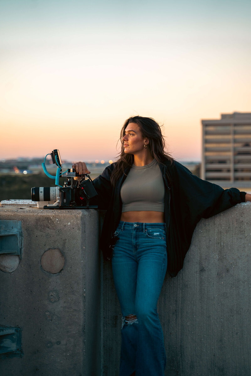 Woman holding camera gear with skyline view in the background