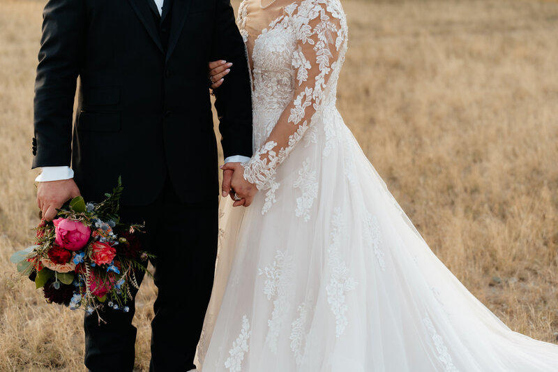 bride and groom embracing in field