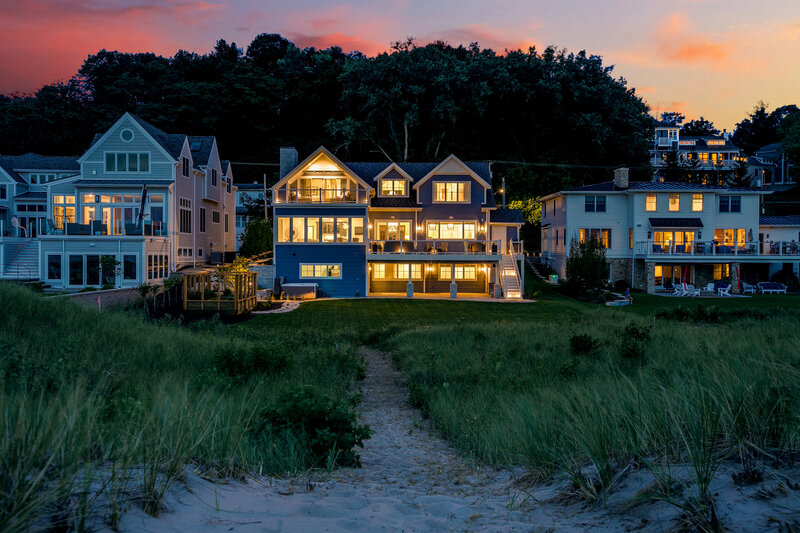 A breathtaking view of a three-story home in Indiana at night, illuminated from within against a stunning backdrop of purple and pink skies. The warm interior lighting enhances the home’s elegance, creating a captivating and serene atmosphere.
