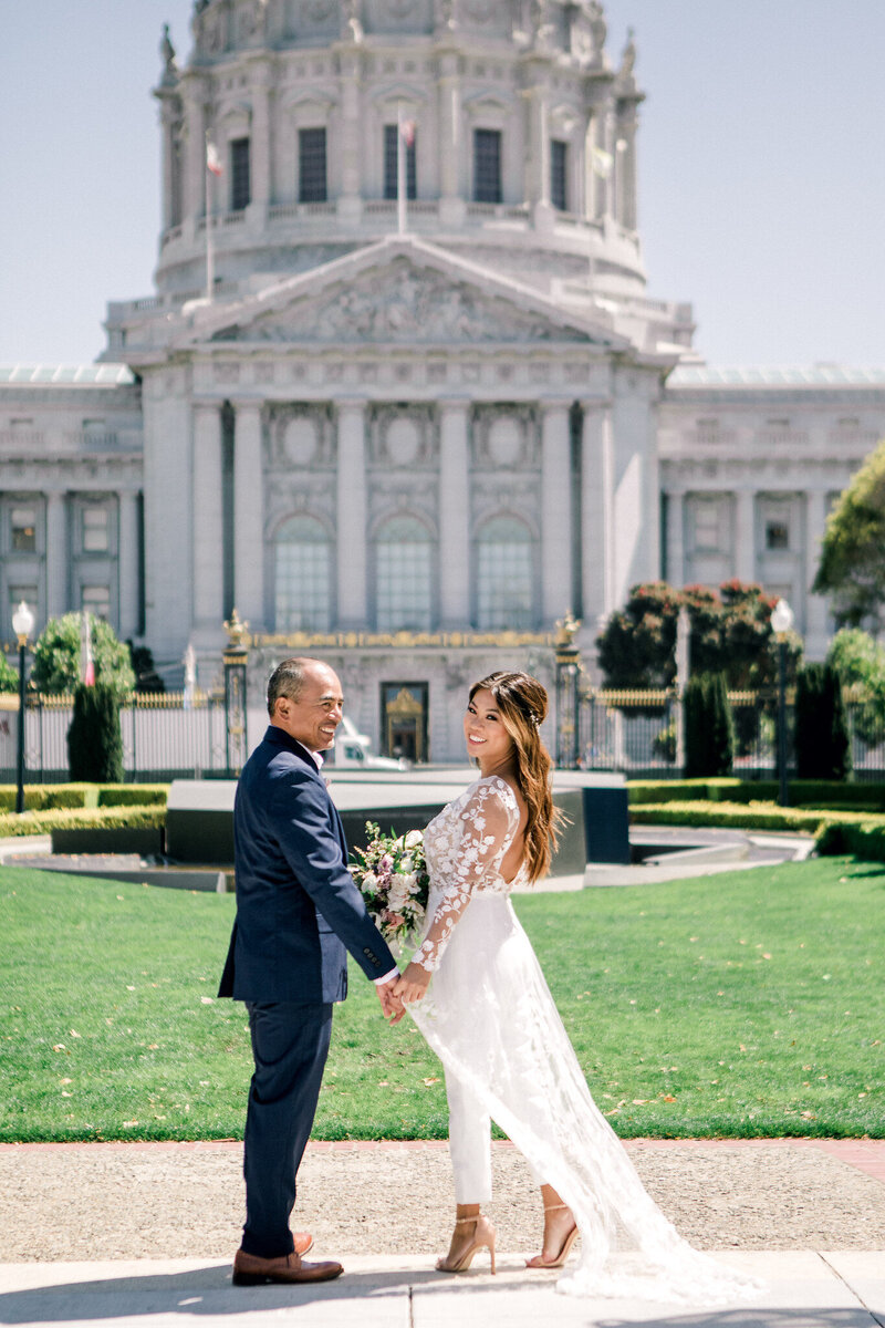 A couple standing in front of city hall looking back at the camera