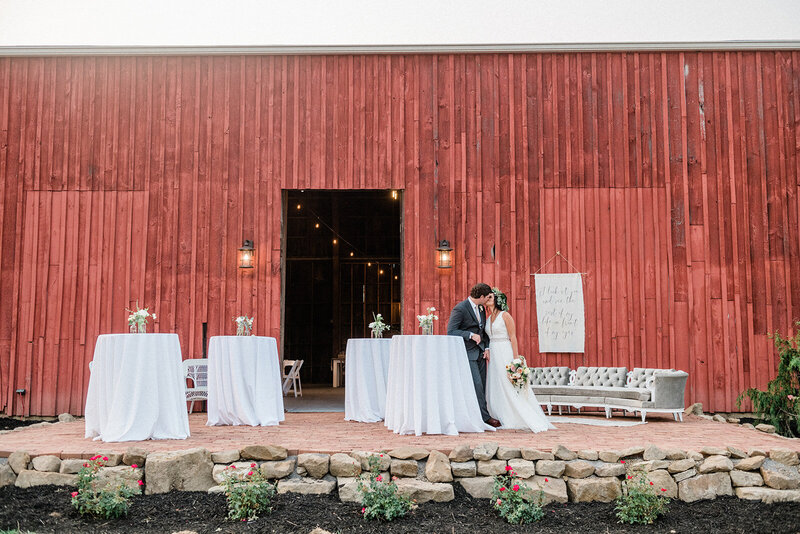 red barn rustic wedding cocktail hour couple kissing