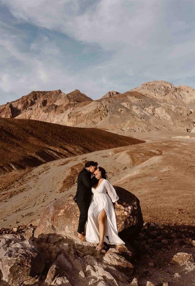 Couple kissing in the desert in their wedding attire on a windy day