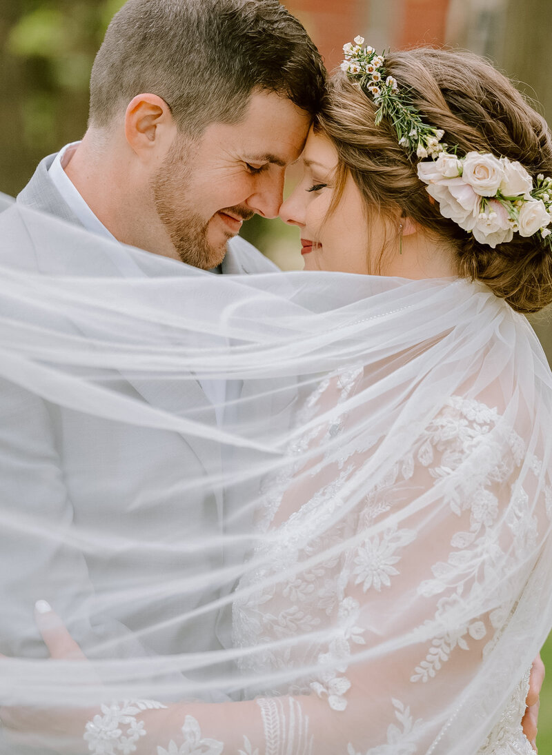 A groom and bride with a flower crown by a Grand Rapids wedding photographer at a summer wedding