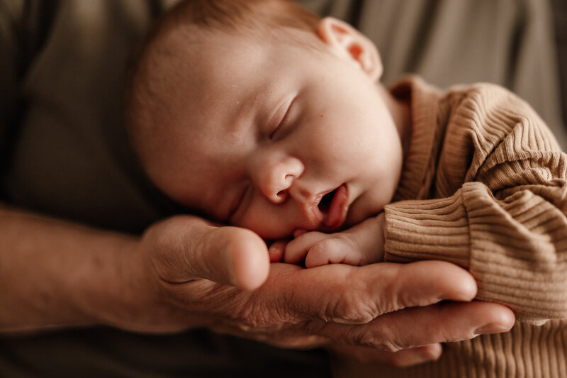 Close-up of a sleeping newborn resting peacefully in the gentle hands of a parent during an in-home newborn photography session in Las Vegas by Angela Wolf Photography.
