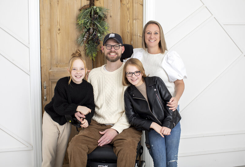 Family of four—mom, dad, and two young daughters—smiling together during a family photo session.