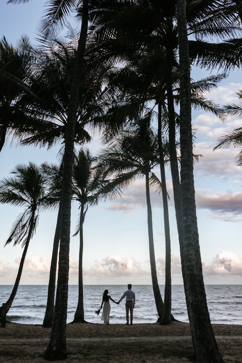 BRide and groom standing outdoors under tall trees