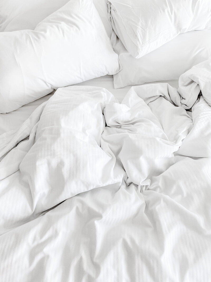 untidy white linens on a bed