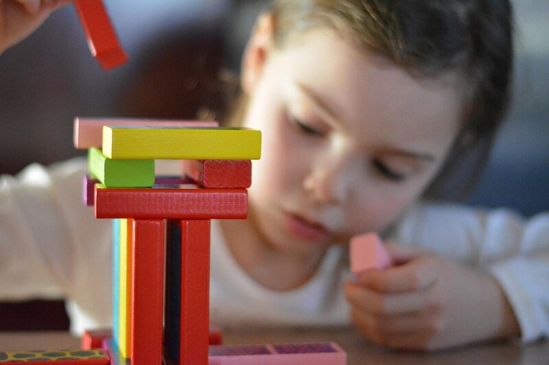 young girl playing with colorful jenga blocks