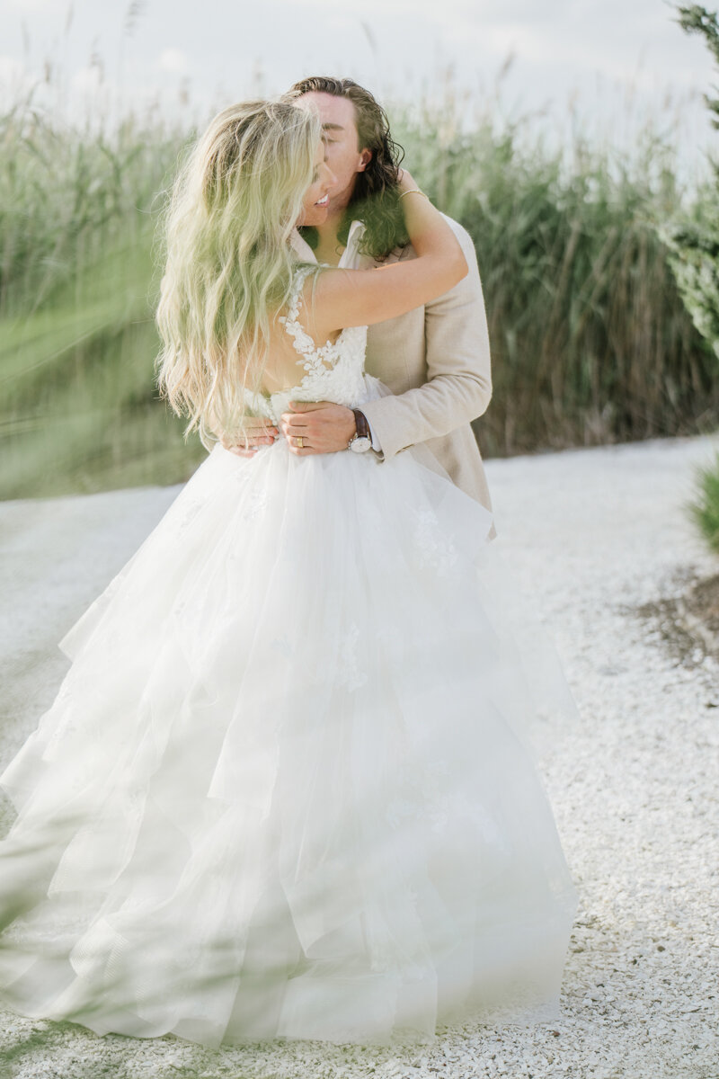 a soft kiss during golden hour outside of the Bonnet Island Estate Chapel. A casual boho beach stye wedding with golden light. 