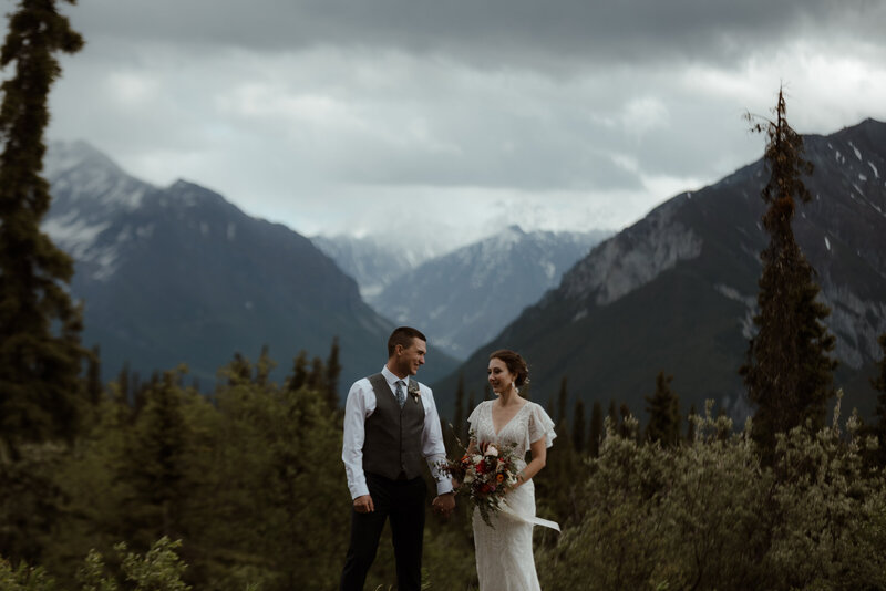 bride and groom standing by mountains