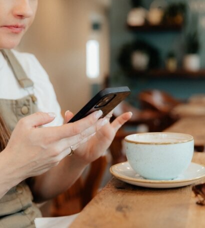 Woman looking at phone next to a latte