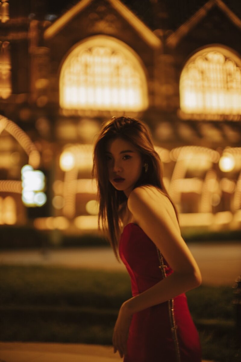 Destination couture photoshoot with a woman in. a red gown at night in the city.