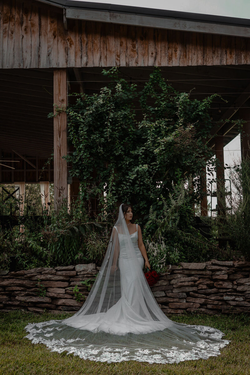 Bride at stone wall in her garden wedding