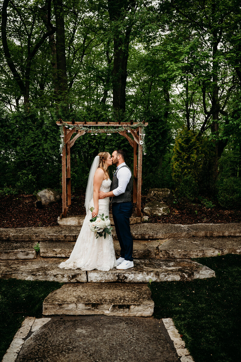 Bride and groom kissing in front of arch
