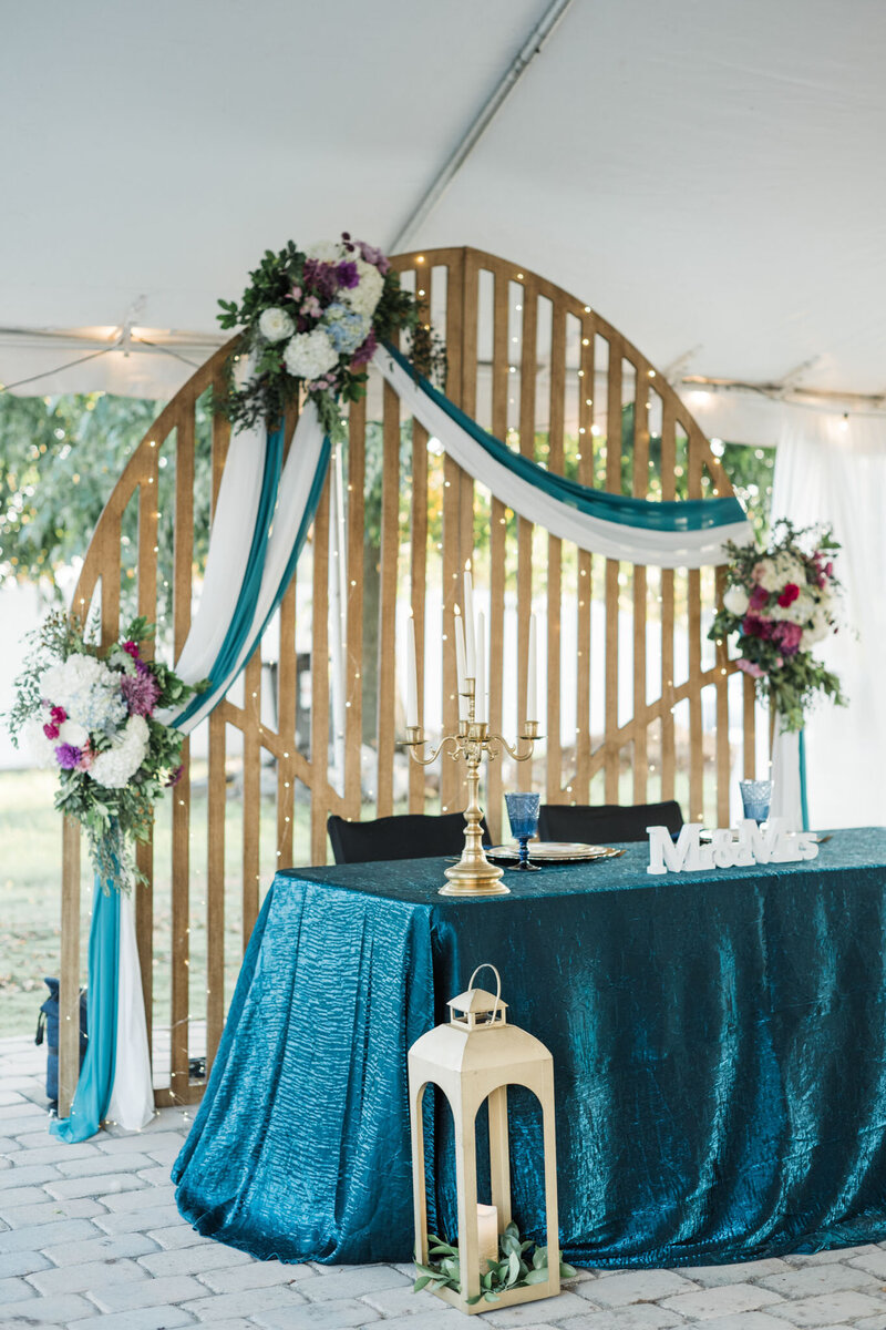 Teal sweetheart table with floral arch