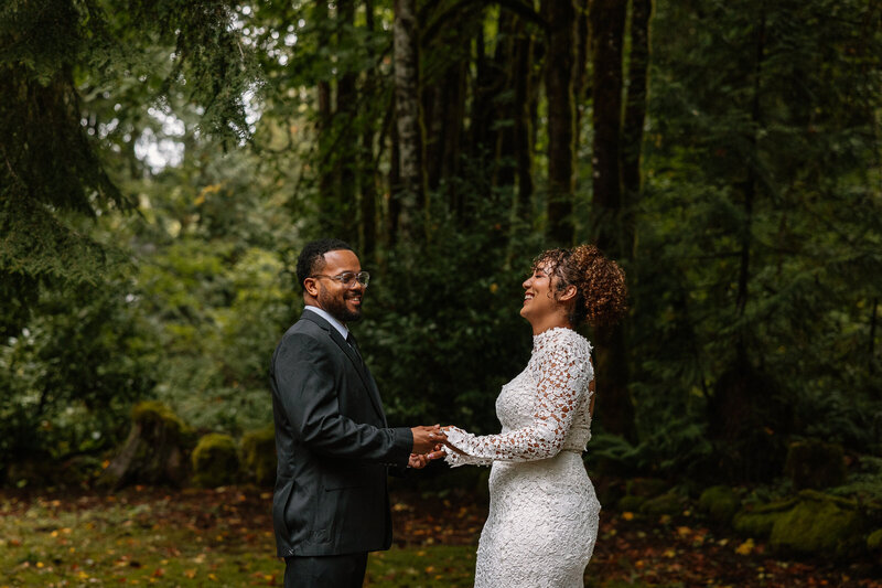 Bride and groom exchange vows in a lush Pacific Northwest forest surrounded by towering evergreens.
