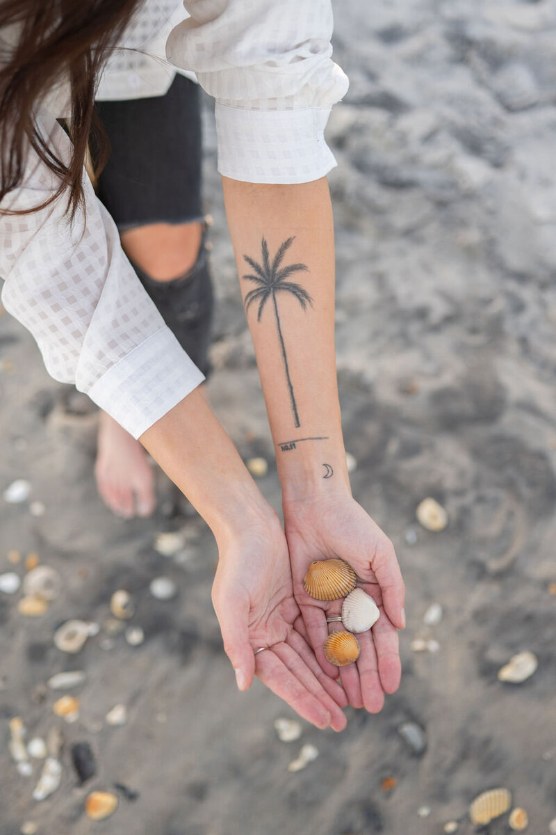outstretched hands holding shells on the beach