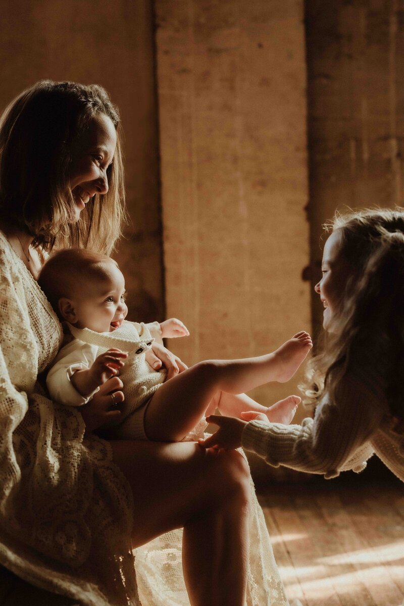 Mother and daughter with newborn baby in golden light, photographed during Sydney petite photography session.