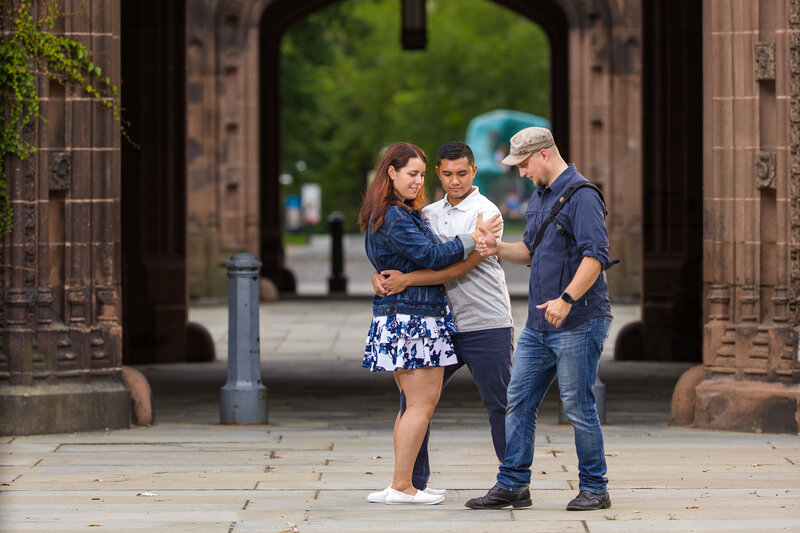 Travis Stitt demonstrating a romantic dip pose to an engaged couple during their engagement session, highlighting his hands-on approach to guiding couples for stunning and memorable photos.