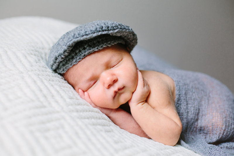 newborn baby boy in a grey knit cap and knit blanket