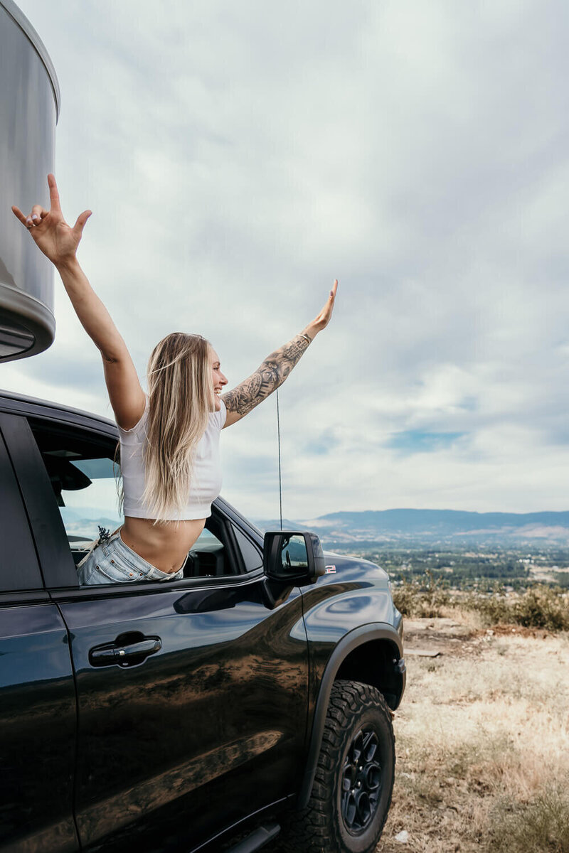 Life coach leaning out the car window with an epic view in the background for adventurous branding photo session