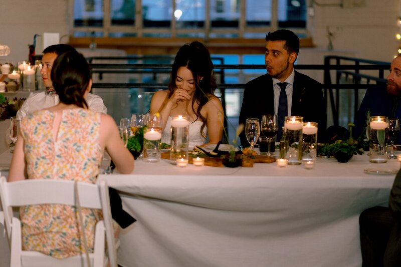 Guests seated at a wedding reception table lit by candlelight.