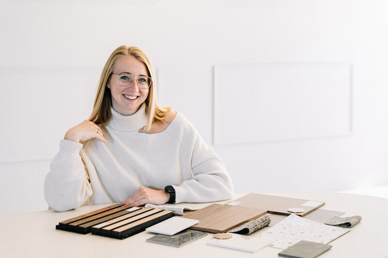 2 blonde meiden, lachen, rechtse zit op kruk, linkse dame heeft hand op schouder, muur is uit mergelsteen