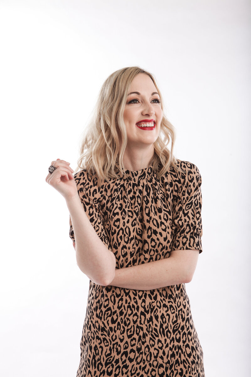A blonde woman in a leopard print laughs