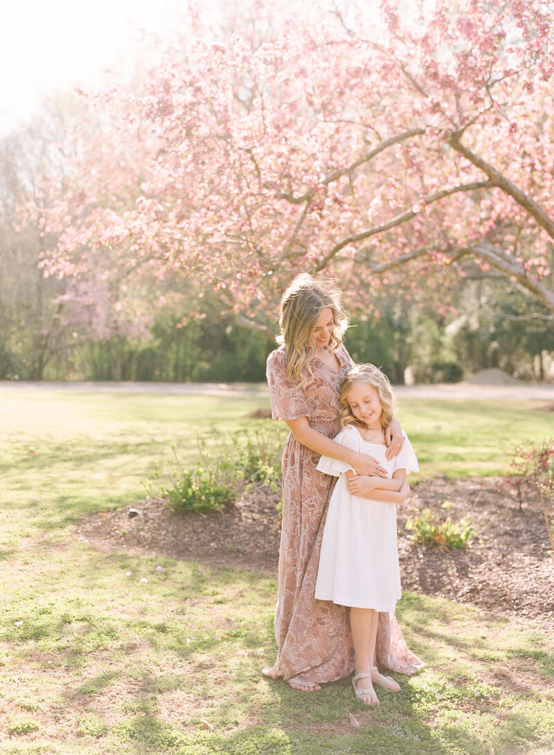 Toddler sitting on pregnant mom's belly grabbing her face and kissing her during a maternity session in Raleigh NC. Photographed by Raleigh maternity photographers A.J. Dunlap Photography.