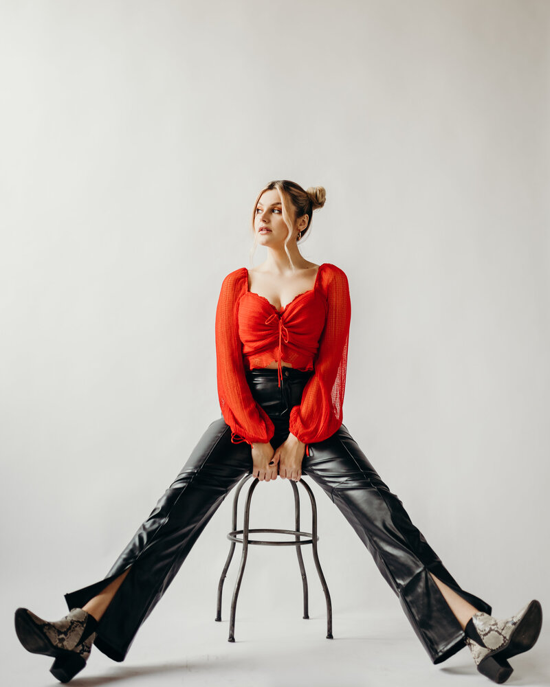 Girl photographed in studio with red shirt and black pants