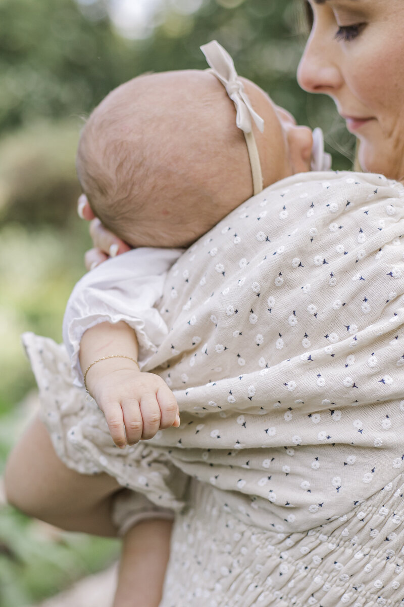 Close up of baby's head laying on mother's shoulder and baby's fingers