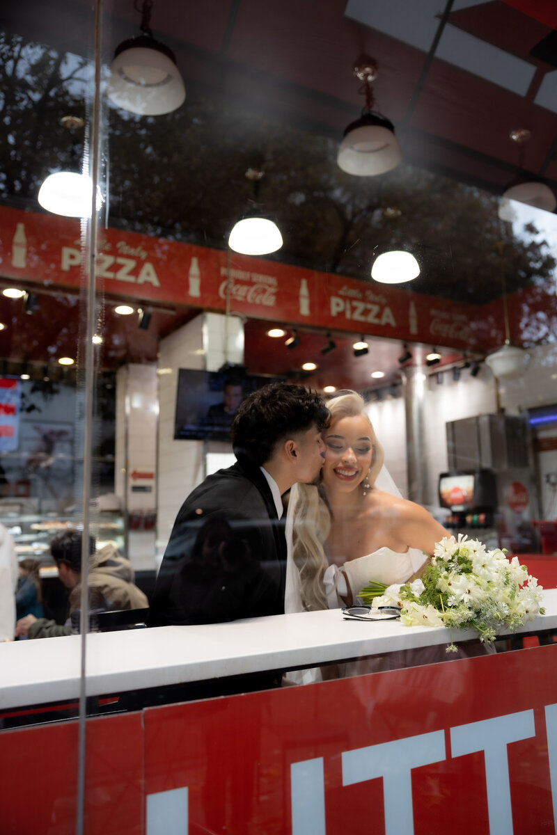Candid shot of the couple laughing together at a table in a classic NYC pizza shop.
