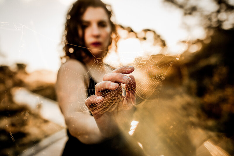Lifestyle family photographer Ashley Kaplan with hand touching spider web