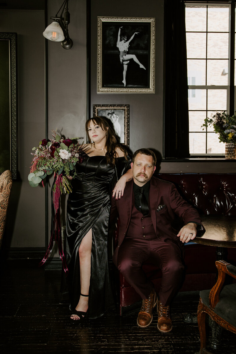 A couple poses next to a dark wall