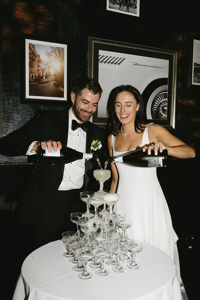 Bride and groom pouring champagne into a champagne tower