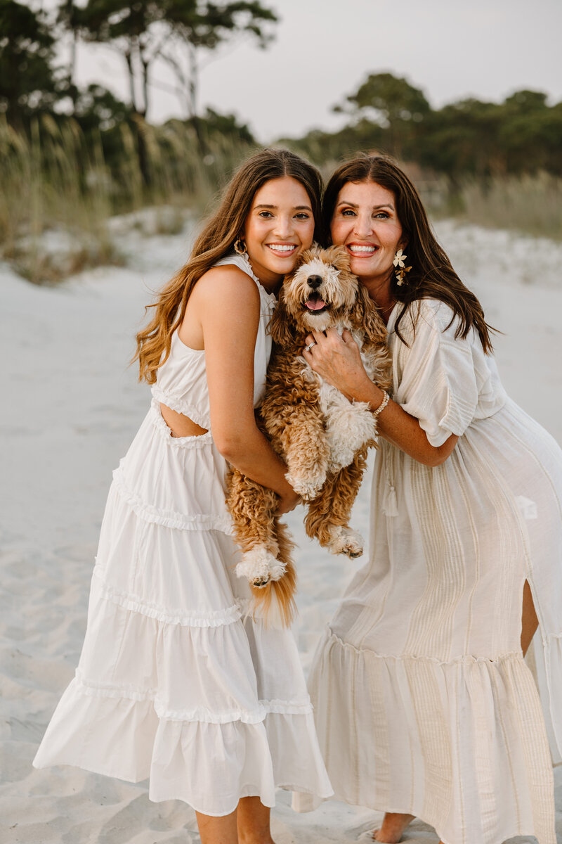 Mom and daughter holding puppy on the beach