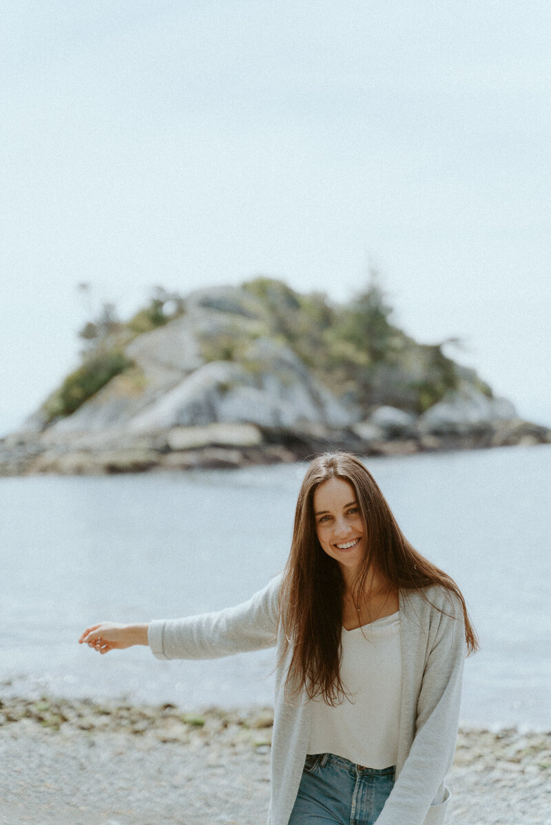Woman with brown curled hair wearing a beige dress in a field with a mountain in the background