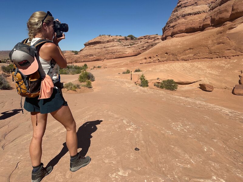 women photographing a rock in Utah desert at arches.