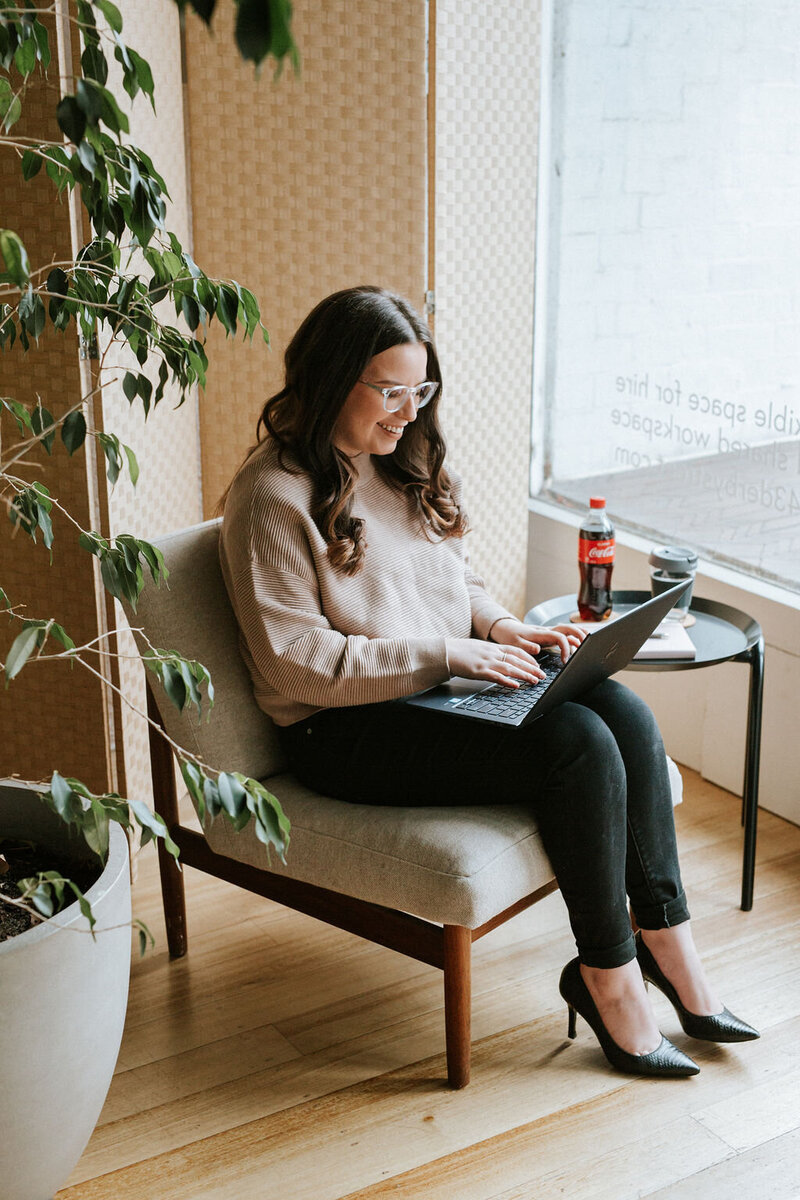 Kirsten from KP Virtual Assistance sitting in a cozy workspace, working on a laptop to set up Studio Ninja systems, reflecting her professional and approachable support for photographers